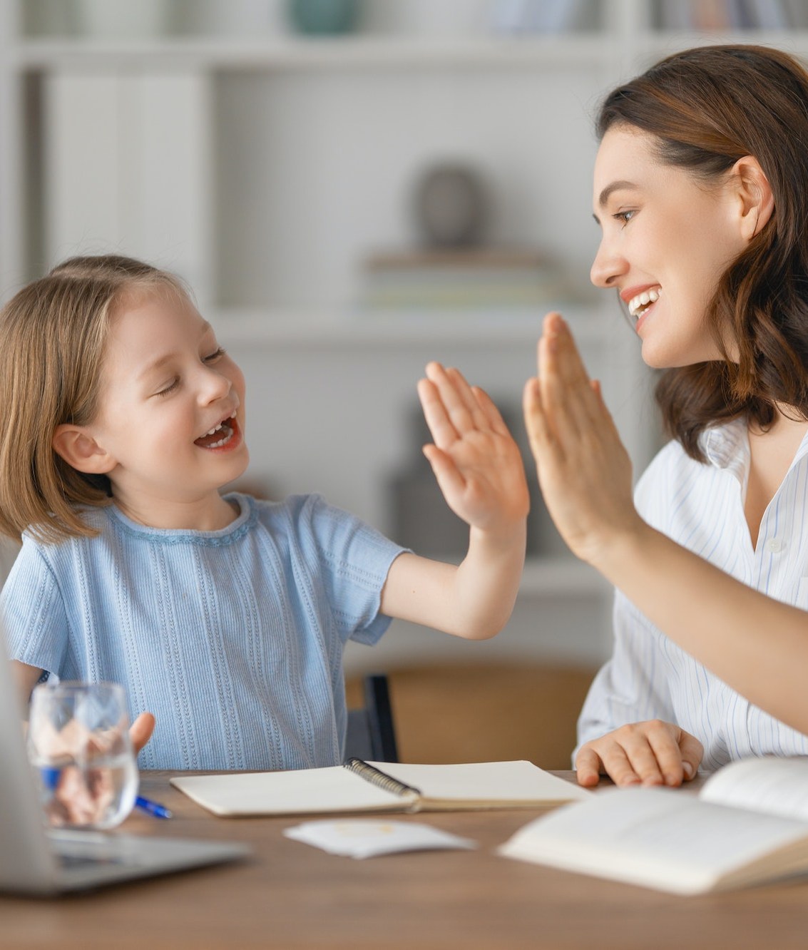 Una madre y su hija chocando las manos en la mesa de su cocina
