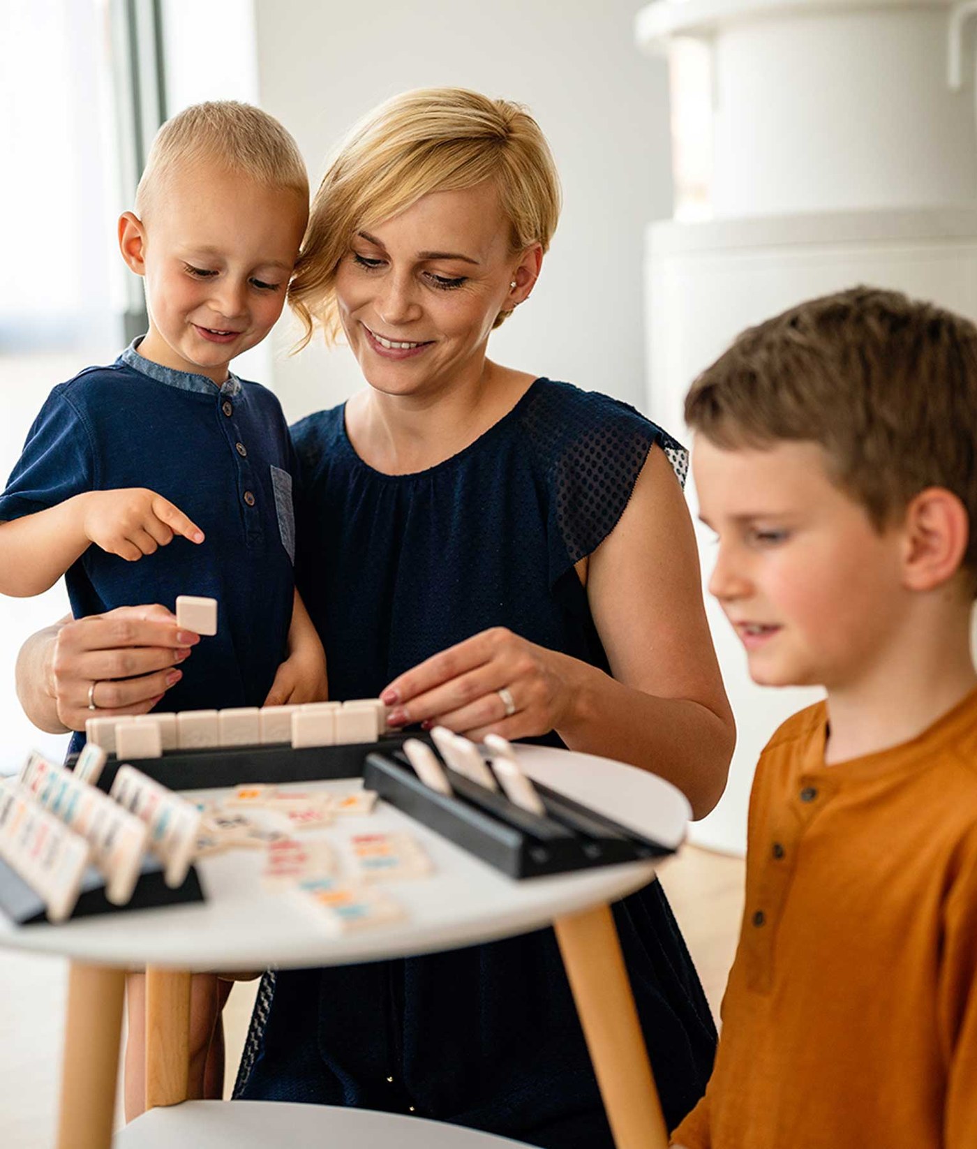 Una madre y sus dos hijos riendo juntos con un juego de mesa en casa