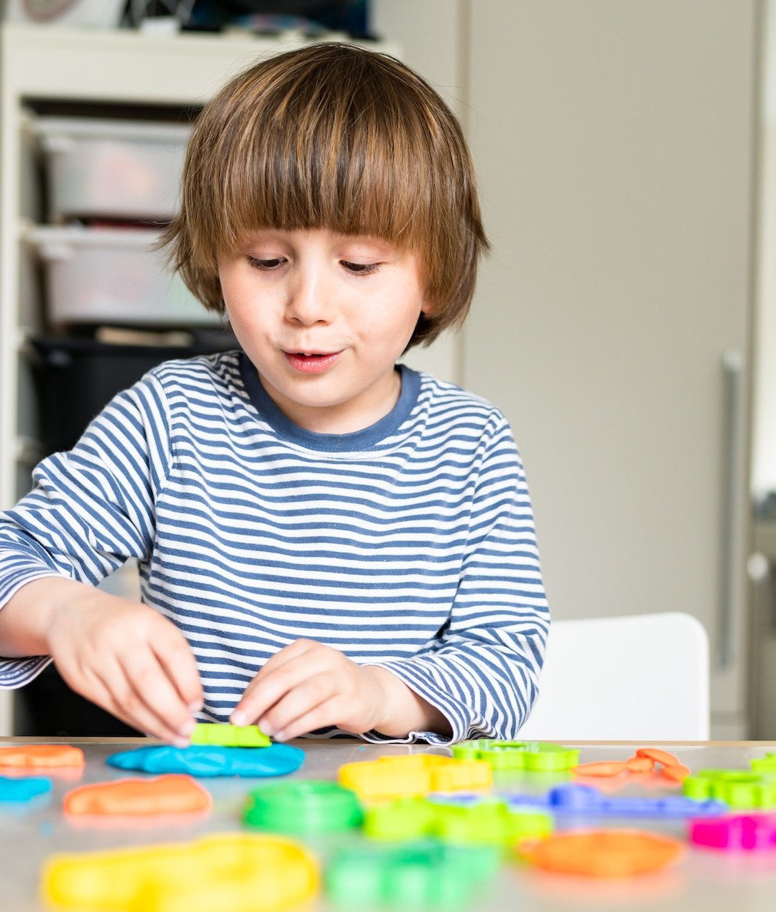 Un niño pequeño jugando en una mesa de manualidades en su propia casa